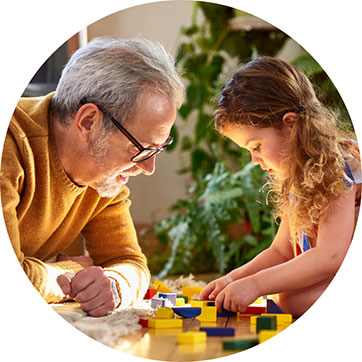 older man and young girl playing with wooden blocks
